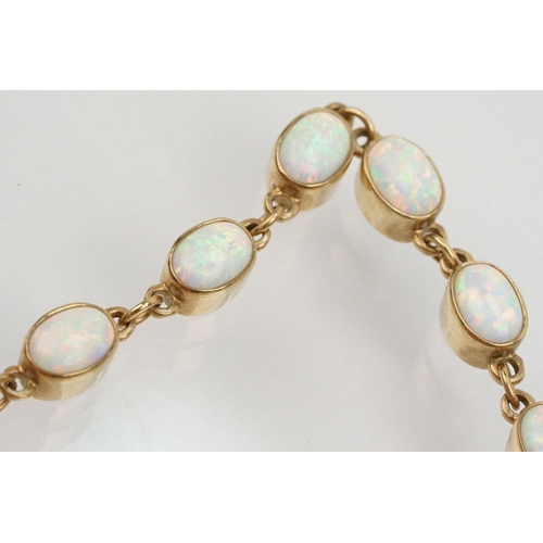 28 - 9ct gold and synthetic opal line bracelet. The bracelet bezel set with oval cabochons. Marked 375 to... 