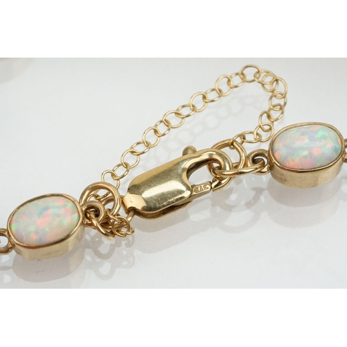 28 - 9ct gold and synthetic opal line bracelet. The bracelet bezel set with oval cabochons. Marked 375 to... 