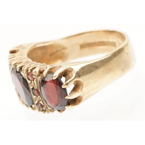 98 - 9ct gold and garnet ring being set with three oval cut garnets with round cut accent stones. Hallmar... 