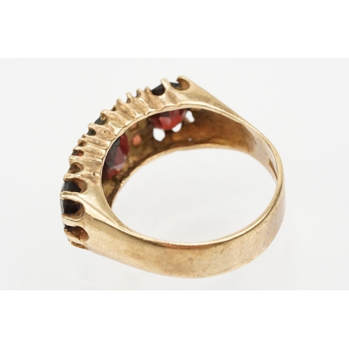 98 - 9ct gold and garnet ring being set with three oval cut garnets with round cut accent stones. Hallmar... 