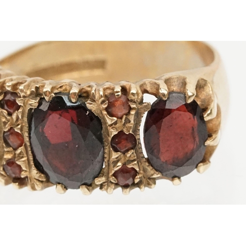 98 - 9ct gold and garnet ring being set with three oval cut garnets with round cut accent stones. Hallmar... 