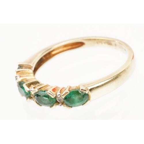 119 - 9ct gold synthetic emerald and diamond line ring. The ring being set with oval cut emeralds with dia... 