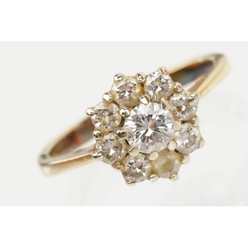 134 - 18ct gold and diamond cluster ring. The ring being set with with a round brilliant cut diamond to ce... 