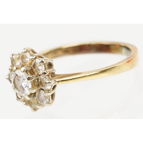 134 - 18ct gold and diamond cluster ring. The ring being set with with a round brilliant cut diamond to ce... 