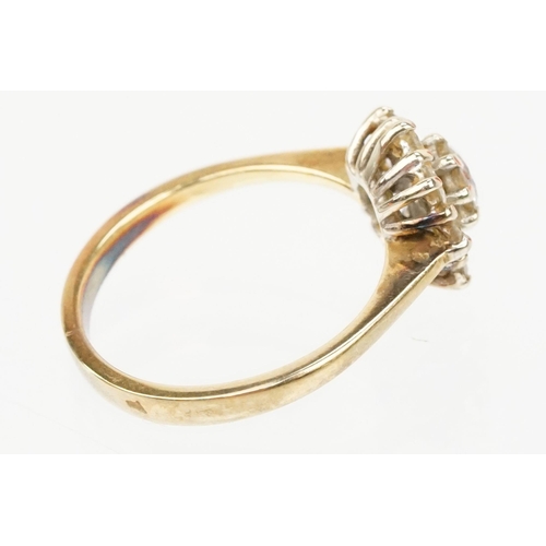 134 - 18ct gold and diamond cluster ring. The ring being set with with a round brilliant cut diamond to ce... 