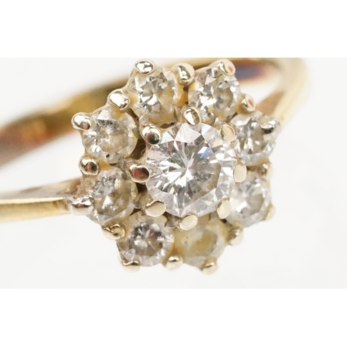 134 - 18ct gold and diamond cluster ring. The ring being set with with a round brilliant cut diamond to ce... 