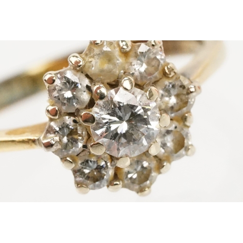 134 - 18ct gold and diamond cluster ring. The ring being set with with a round brilliant cut diamond to ce... 