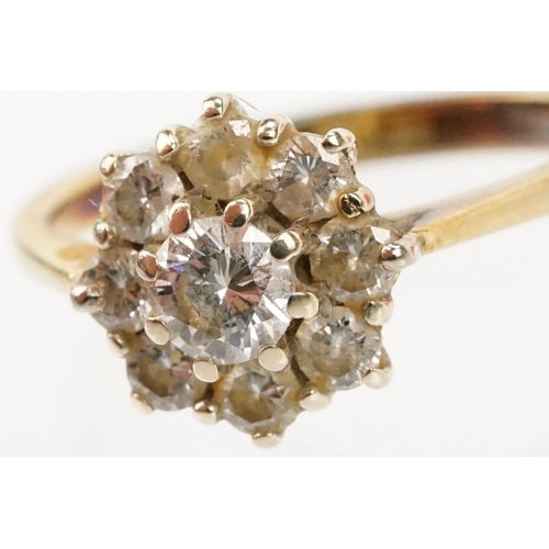 134 - 18ct gold and diamond cluster ring. The ring being set with with a round brilliant cut diamond to ce... 