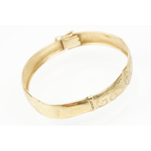 184 - 9ct gold hinged bangle bracelet engraved with foliate scrolls. Marked 375. Measures 5.8cm wide.