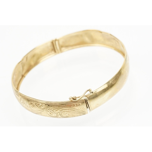 184 - 9ct gold hinged bangle bracelet engraved with foliate scrolls. Marked 375. Measures 5.8cm wide.