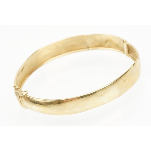 184 - 9ct gold hinged bangle bracelet engraved with foliate scrolls. Marked 375. Measures 5.8cm wide.