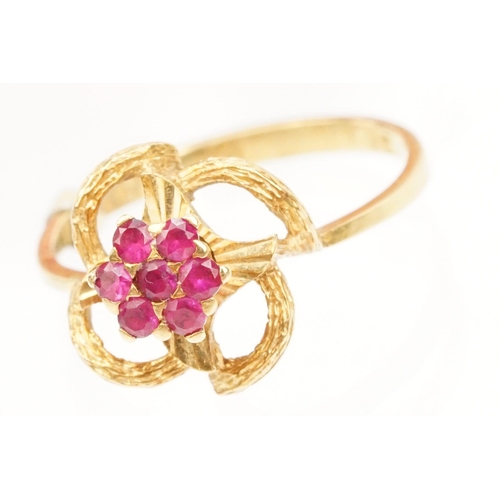 185 - 18ct gold and ruby cluster ring having a cluster of round cut rubies to centre with a pierced floral... 