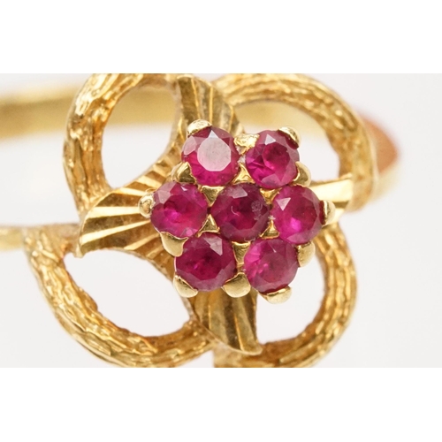 185 - 18ct gold and ruby cluster ring having a cluster of round cut rubies to centre with a pierced floral... 