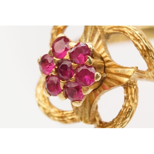 185 - 18ct gold and ruby cluster ring having a cluster of round cut rubies to centre with a pierced floral... 