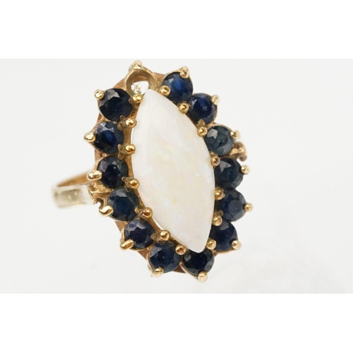 187 - 9ct gold opal and sapphire cluster ring. The ring being set with a marquise opal cabochon to centre ... 