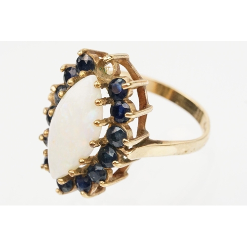 187 - 9ct gold opal and sapphire cluster ring. The ring being set with a marquise opal cabochon to centre ... 