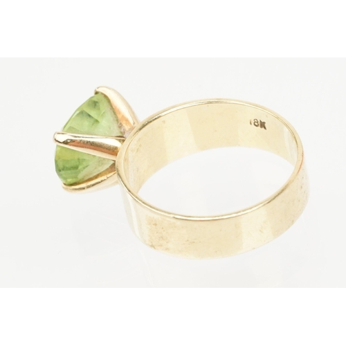 41 - 18ct gold and peridot dress ring. The ring being set with an oval cut peridot in a four prong settin... 