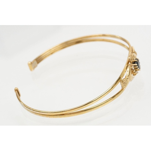 74 - 9ct gold Claddagh bangle bracelet being set with a heart cut blue stone to centre with cz accent sto... 