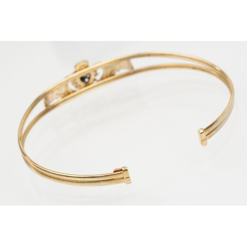 74 - 9ct gold Claddagh bangle bracelet being set with a heart cut blue stone to centre with cz accent sto... 