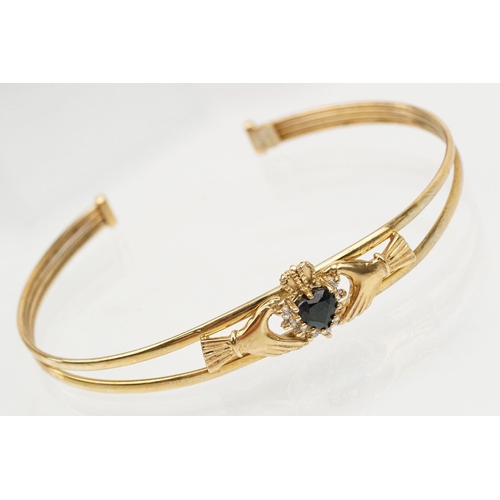 74 - 9ct gold Claddagh bangle bracelet being set with a heart cut blue stone to centre with cz accent sto... 