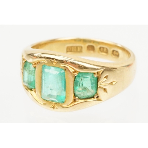 9 - 18ct gold and emerald three stone ring. The ring being bezel set with three step cut emeralds within... 