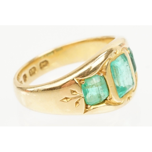 9 - 18ct gold and emerald three stone ring. The ring being bezel set with three step cut emeralds within... 