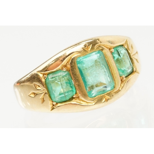 9 - 18ct gold and emerald three stone ring. The ring being bezel set with three step cut emeralds within... 