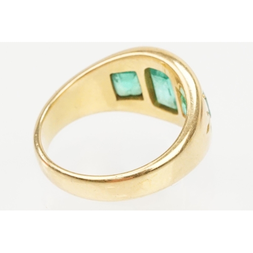 9 - 18ct gold and emerald three stone ring. The ring being bezel set with three step cut emeralds within... 