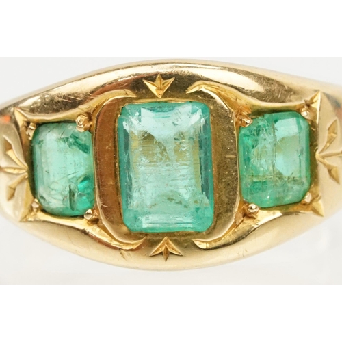 9 - 18ct gold and emerald three stone ring. The ring being bezel set with three step cut emeralds within... 