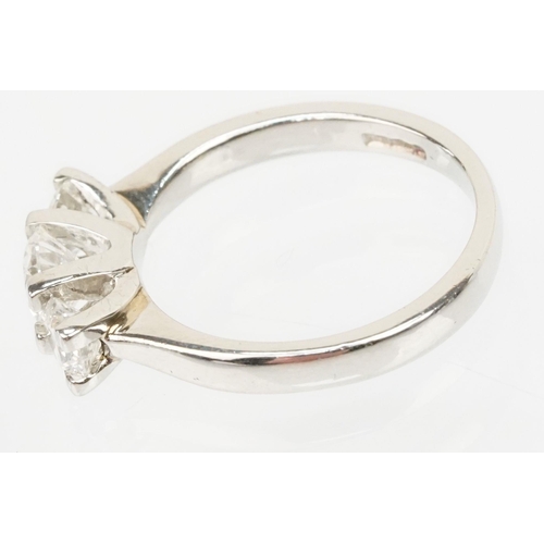 12 - Platinum and diamond three stone ring. The ring being set with a round brilliant cut diamond to cent... 