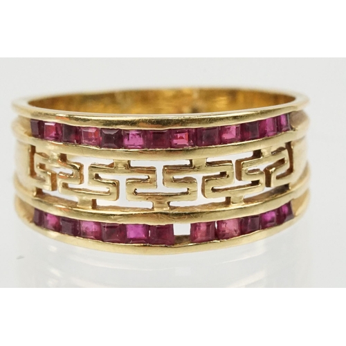 167 - 18ct gold and ruby ring having a pierced Greek key design head with two rows on channel set step cut... 