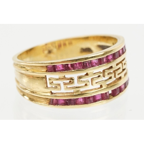 167 - 18ct gold and ruby ring having a pierced Greek key design head with two rows on channel set step cut... 