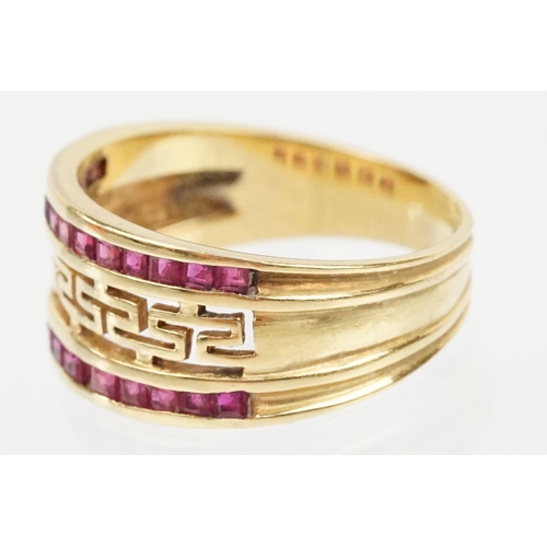 167 - 18ct gold and ruby ring having a pierced Greek key design head with two rows on channel set step cut... 