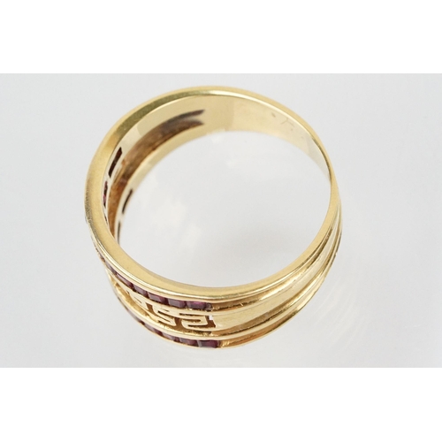 167 - 18ct gold and ruby ring having a pierced Greek key design head with two rows on channel set step cut... 