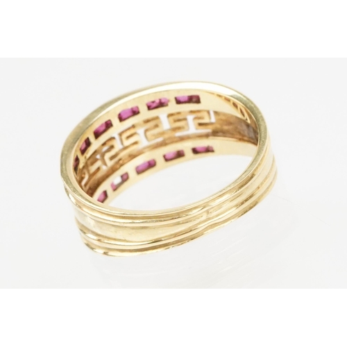 167 - 18ct gold and ruby ring having a pierced Greek key design head with two rows on channel set step cut... 