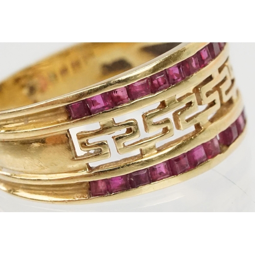 167 - 18ct gold and ruby ring having a pierced Greek key design head with two rows on channel set step cut... 