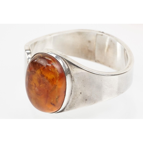 175 - Silver and amber bangle bracelet having a large amber cabochon to the head and hinged opening to the... 