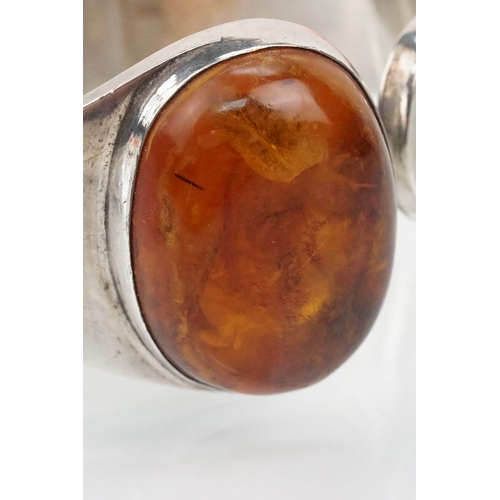 175 - Silver and amber bangle bracelet having a large amber cabochon to the head and hinged opening to the... 