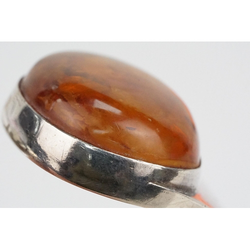 175 - Silver and amber bangle bracelet having a large amber cabochon to the head and hinged opening to the... 