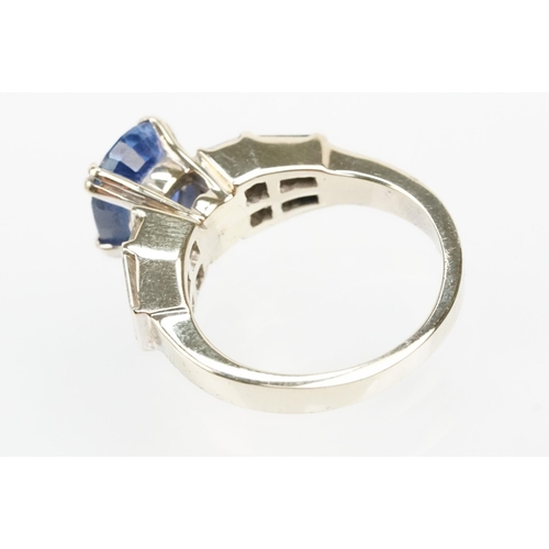 2 - 18ct white gold, sapphire and diamond ring. The ring being set with an oval mixed cut blue sapphire ... 