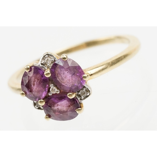 249 - 9ct gold Comeria garnet and diamond cluster ring. The ring being set with three oval cut purple garn... 