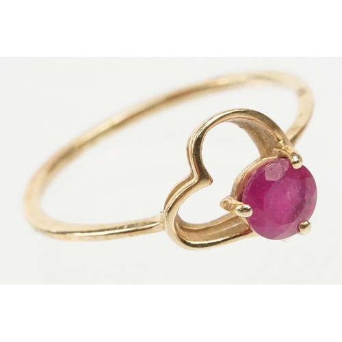 252 - 9ct gold and ruby ring. The ring being set with a round cut ruby within a pierced heart head on a pl... 