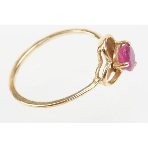 252 - 9ct gold and ruby ring. The ring being set with a round cut ruby within a pierced heart head on a pl... 