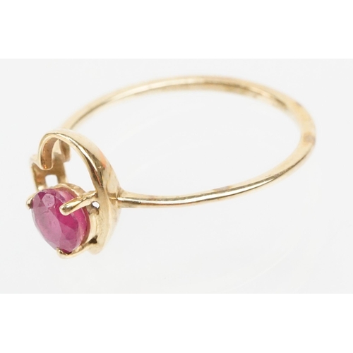 252 - 9ct gold and ruby ring. The ring being set with a round cut ruby within a pierced heart head on a pl... 