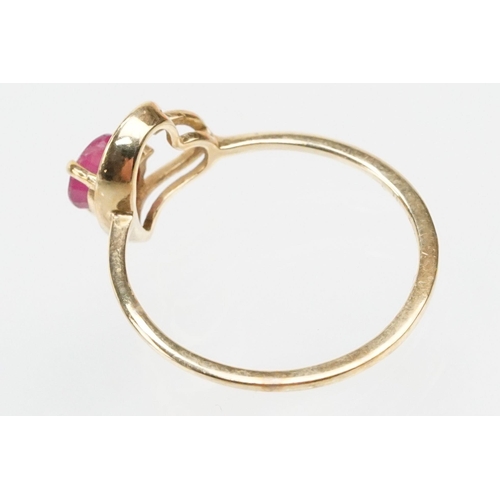 252 - 9ct gold and ruby ring. The ring being set with a round cut ruby within a pierced heart head on a pl... 