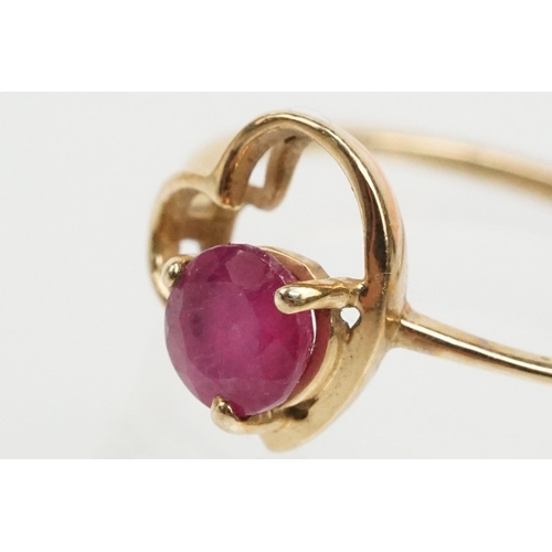 252 - 9ct gold and ruby ring. The ring being set with a round cut ruby within a pierced heart head on a pl... 