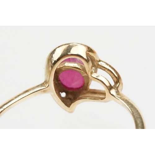 252 - 9ct gold and ruby ring. The ring being set with a round cut ruby within a pierced heart head on a pl... 