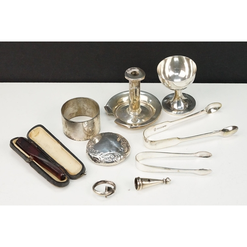 360 - Collection of silver items to include an egg cup, small chamberstick, napkin ring, and jar lid. All ... 