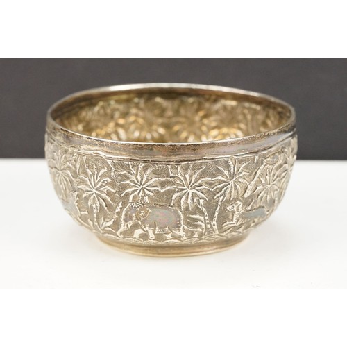 372 - Indian white metal jug and bowl, each having repousse details featuring animals and palm trees. Both... 