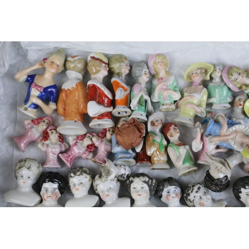 139 - A large collection of antique ceramic pin cushion dolls and doll heads of various sizes and styles.